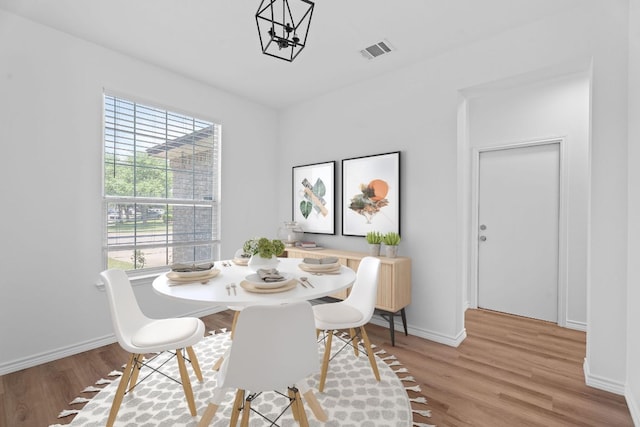 dining room featuring baseboards, light wood finished floors, and visible vents