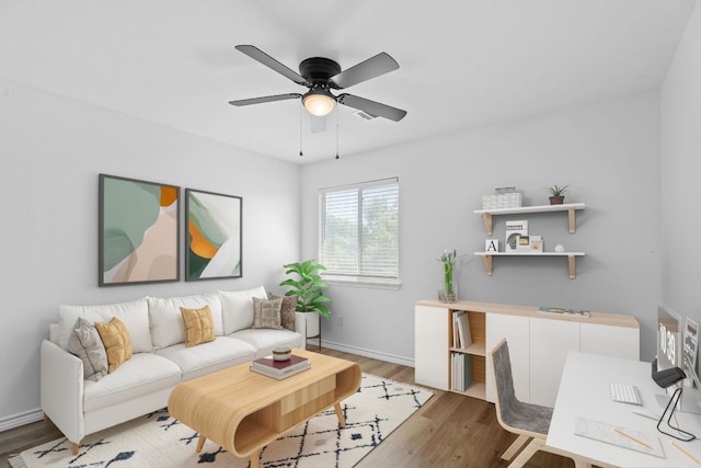 living area featuring baseboards, a ceiling fan, and light wood-type flooring