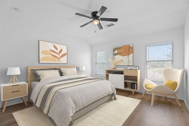 bedroom featuring vaulted ceiling, wood finished floors, visible vents, baseboards, and ceiling fan