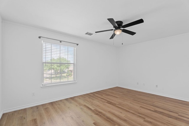 empty room featuring light wood finished floors, visible vents, crown molding, baseboards, and ceiling fan
