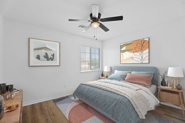 bedroom with wood finished floors, visible vents, a ceiling fan, and baseboards