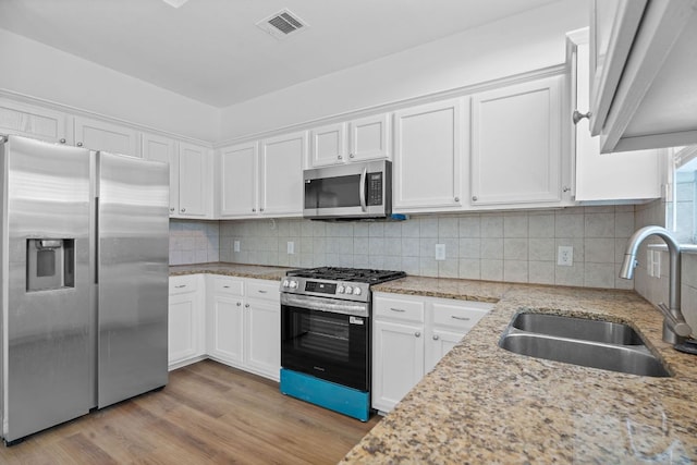 kitchen featuring white cabinets, stainless steel appliances, a sink, and light wood finished floors