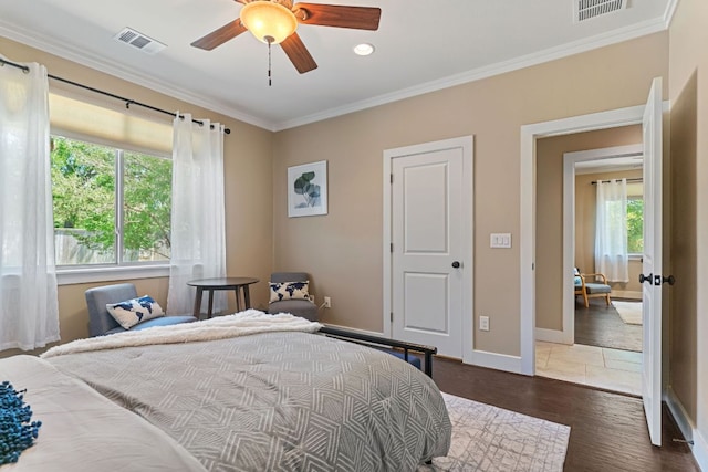 bedroom featuring wood finished floors, visible vents, crown molding, and baseboards