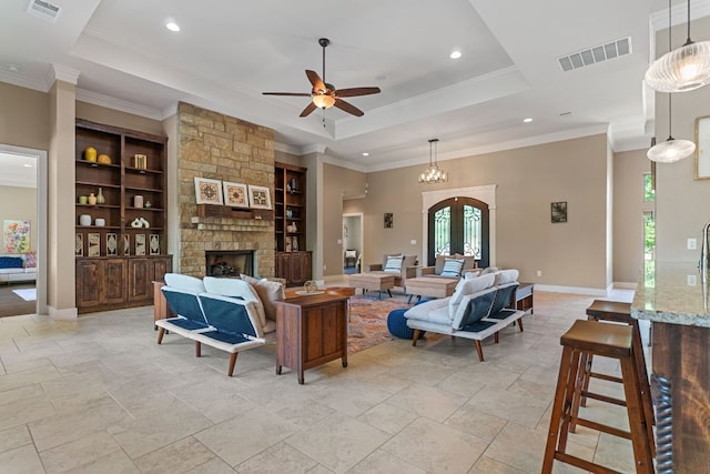 living area featuring a tray ceiling, visible vents, built in features, and a healthy amount of sunlight