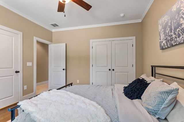 bedroom featuring a ceiling fan, visible vents, a closet, and crown molding