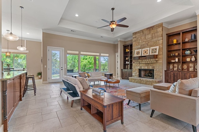 living area featuring ceiling fan, a stone fireplace, a tray ceiling, and recessed lighting