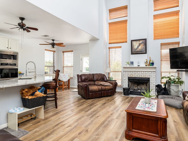 16019 Dark Ln, Austin, TX 78717 - living room with ceiling fan, light wood-style flooring, a brick fireplace, baseboards, and a high ceiling