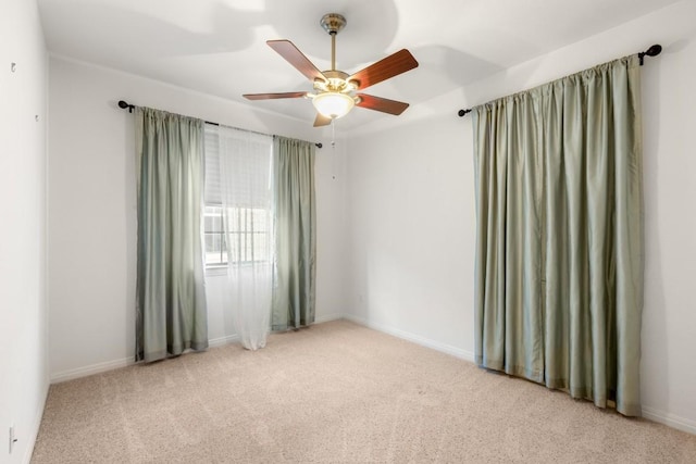 carpeted empty room with ceiling fan and baseboards