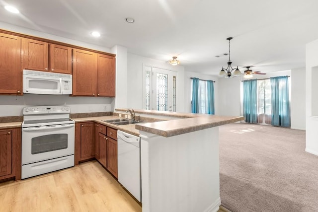 kitchen with brown cabinets, open floor plan, a sink, and white appliances