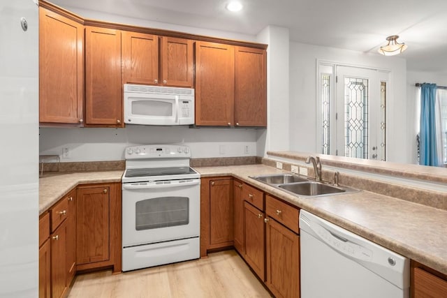 kitchen with light wood-style flooring, a sink, recessed lighting, white appliances, and brown cabinetry