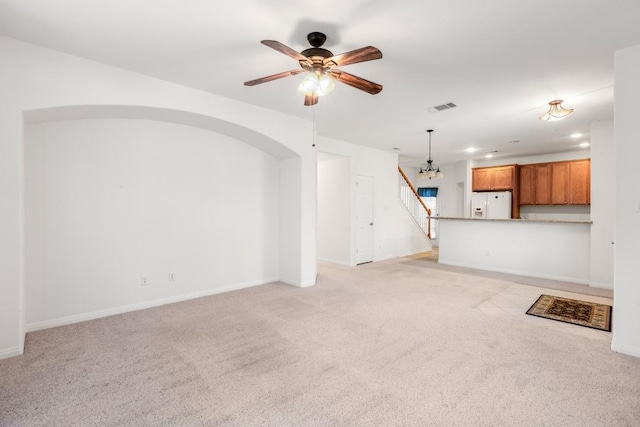unfurnished living room with light colored carpet, baseboards, a ceiling fan, and visible vents