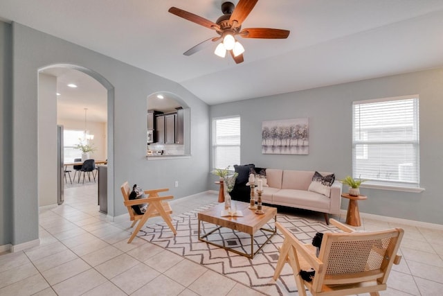 living area with lofted ceiling, arched walkways, light tile patterned flooring, baseboards, and ceiling fan