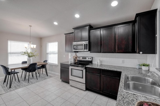 kitchen featuring a sink, an inviting chandelier, backsplash, baseboards, and appliances with stainless steel finishes