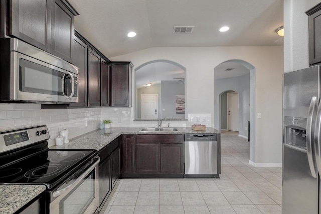 kitchen featuring a sink, vaulted ceiling, visible vents, light stone counters, and appliances with stainless steel finishes