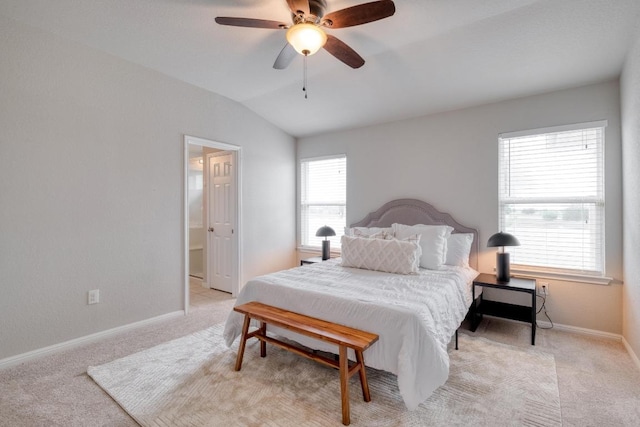 bedroom with a ceiling fan, ensuite bathroom, light carpet, baseboards, and lofted ceiling