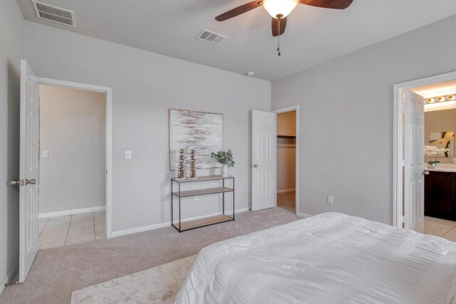 bedroom with light tile patterned floors, ensuite bath, visible vents, and light colored carpet