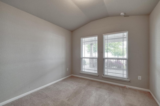 unfurnished room featuring baseboards, lofted ceiling, and light colored carpet