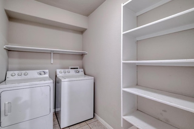 laundry area featuring washing machine and dryer, baseboards, laundry area, and light tile patterned floors