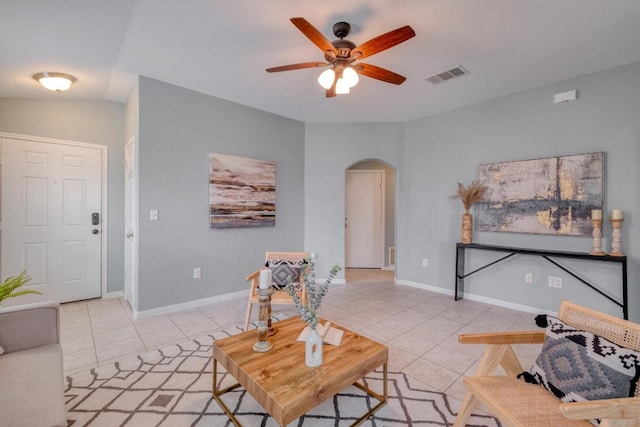 living area featuring light tile patterned floors, ceiling fan, arched walkways, baseboards, and visible vents