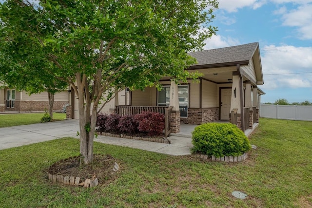 view of front of house featuring covered porch, a front yard, concrete driveway, and fence