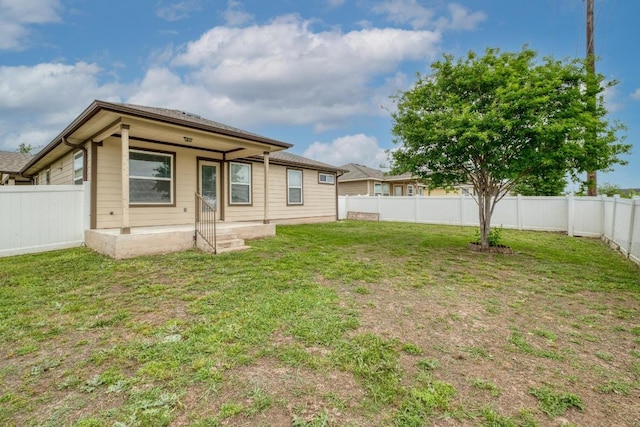 rear view of house featuring a fenced backyard and a lawn