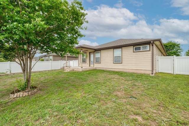back of property with a gate, a lawn, and a fenced backyard