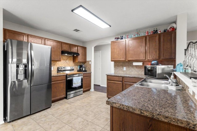 13625 Coomer Path, Pflugerville, TX 78660 - kitchen with appliances with stainless steel finishes, under cabinet range hood, arched walkways, and tasteful backsplash