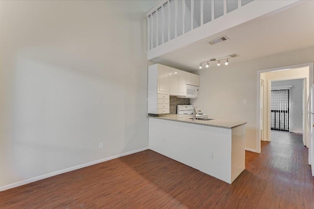 2815 Rio Grande St Unit 211, Austin, TX 78705 - kitchen featuring white microwave, dark wood-type flooring, a peninsula, white cabinetry, and backsplash