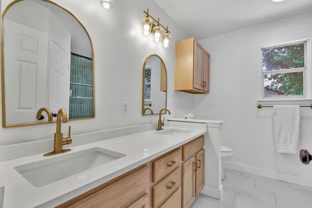 full bathroom with double vanity, toilet, baseboards, and a sink