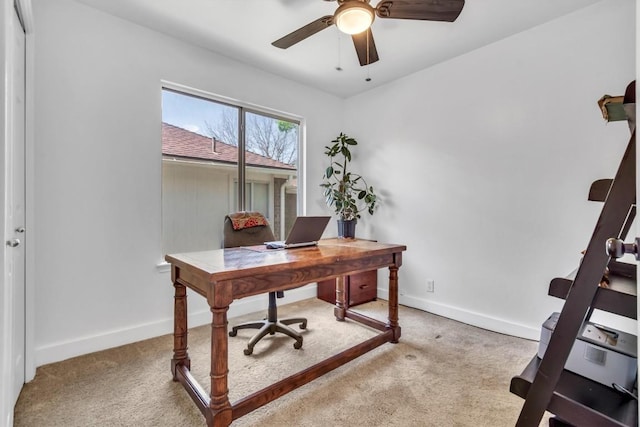 carpeted home office featuring baseboards and ceiling fan