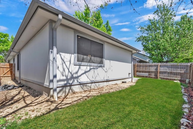 view of side of property featuring fence and a lawn