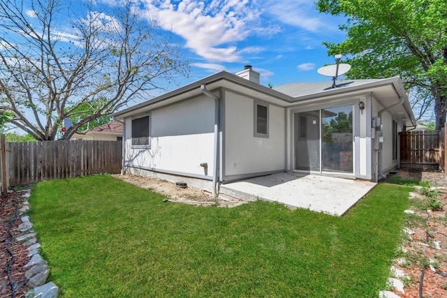back of property with a yard, a fenced backyard, a patio, and a chimney