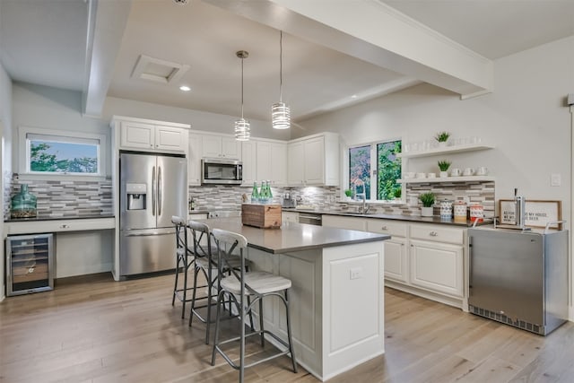 22401 Felicia Dr, Spicewood, TX 78669 - kitchen featuring appliances with stainless steel finishes, wine cooler, backsplash, a breakfast bar area, and white cabinetry