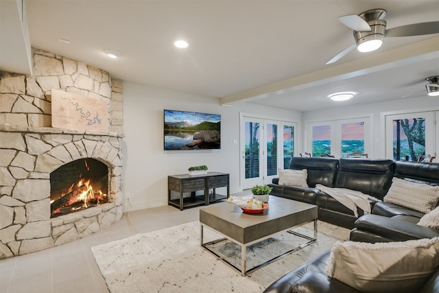 living area with ceiling fan, tile patterned flooring, and a stone fireplace