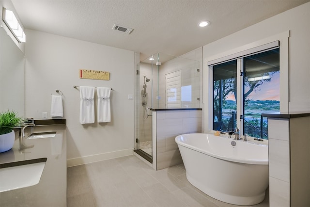 bathroom featuring a shower stall, tile patterned floors, a freestanding bath, visible vents, and a textured ceiling