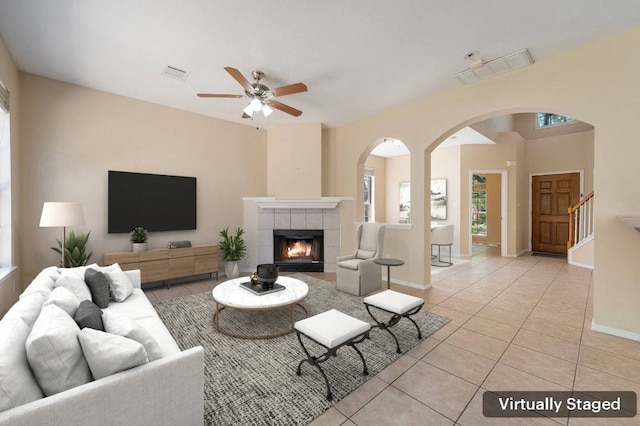 13321 Kirkglen Dr, Austin, TX 78727 - living area featuring light tile patterned floors, arched walkways, a tiled fireplace, a ceiling fan, and stairway