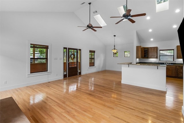 2105 Brackenridge St, Austin, TX 78704 - unfurnished living room with high vaulted ceiling, a ceiling fan, a skylight, plenty of natural light, and light wood-style floors