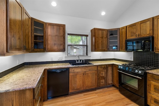 2105 Brackenridge St, Austin, TX 78704 - kitchen with black appliances, light wood-style floors, glass insert cabinets, vaulted ceiling, and recessed lighting