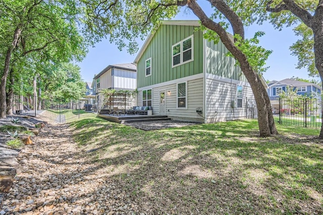 rear view of house featuring a fenced backyard, a deck, board and batten siding, and a lawn