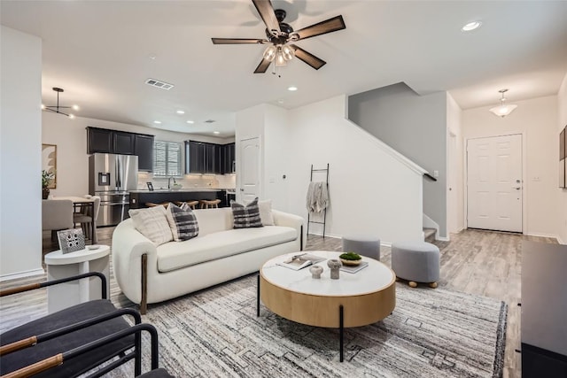 living area with light wood-type flooring, visible vents, recessed lighting, a ceiling fan, and stairway