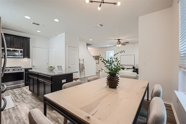 dining room featuring light wood-type flooring, visible vents, baseboards, and ceiling fan