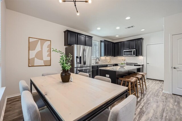 10504 Abana Way, Austin, TX 78748 - kitchen featuring stainless steel appliances, a kitchen island, a kitchen bar, light wood finished floors, and recessed lighting