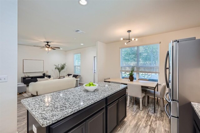 10504 Abana Way, Austin, TX 78748 - kitchen with freestanding refrigerator, light wood-style flooring, light stone counters, a center island, and ceiling fan