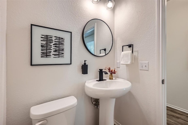 half bathroom featuring wood finished floors and toilet