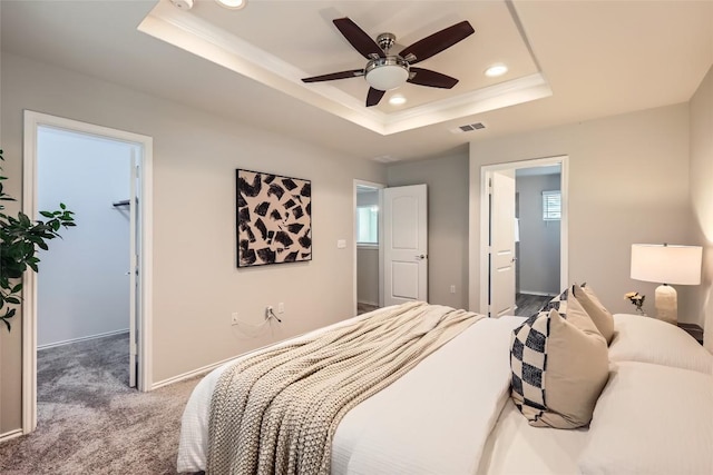 bedroom with a walk in closet, a tray ceiling, carpet flooring, visible vents, and recessed lighting