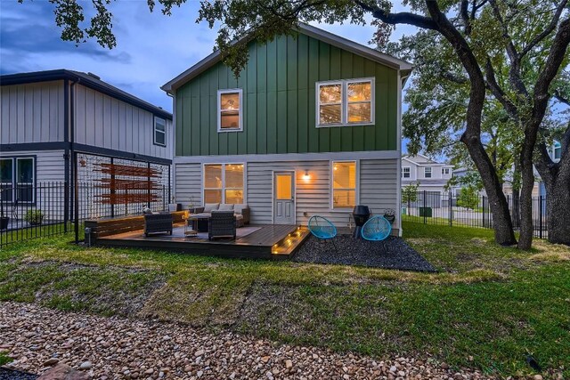 back of house with a lawn, board and batten siding, fence, an outdoor hangout area, and a wooden deck