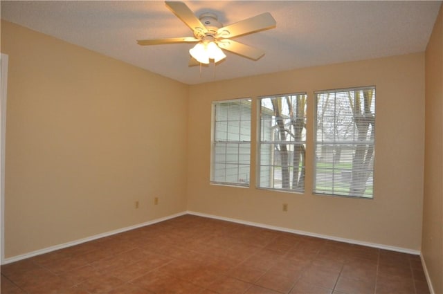 tiled spare room with ceiling fan and baseboards
