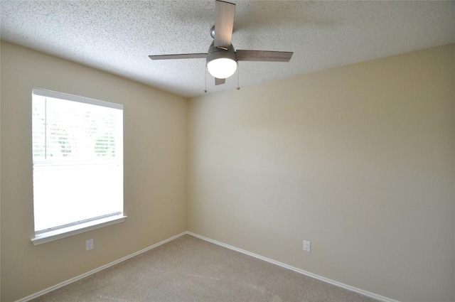empty room with baseboards, a textured ceiling, a ceiling fan, and light colored carpet