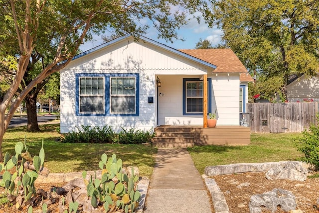 bungalow-style house with a front lawn and fence