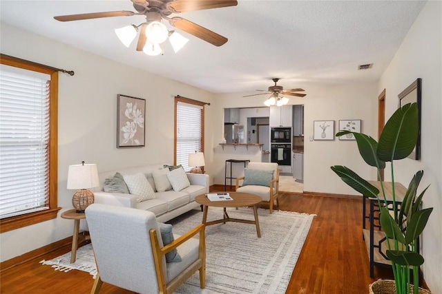 living area featuring ceiling fan, baseboards, light wood finished floors, and visible vents